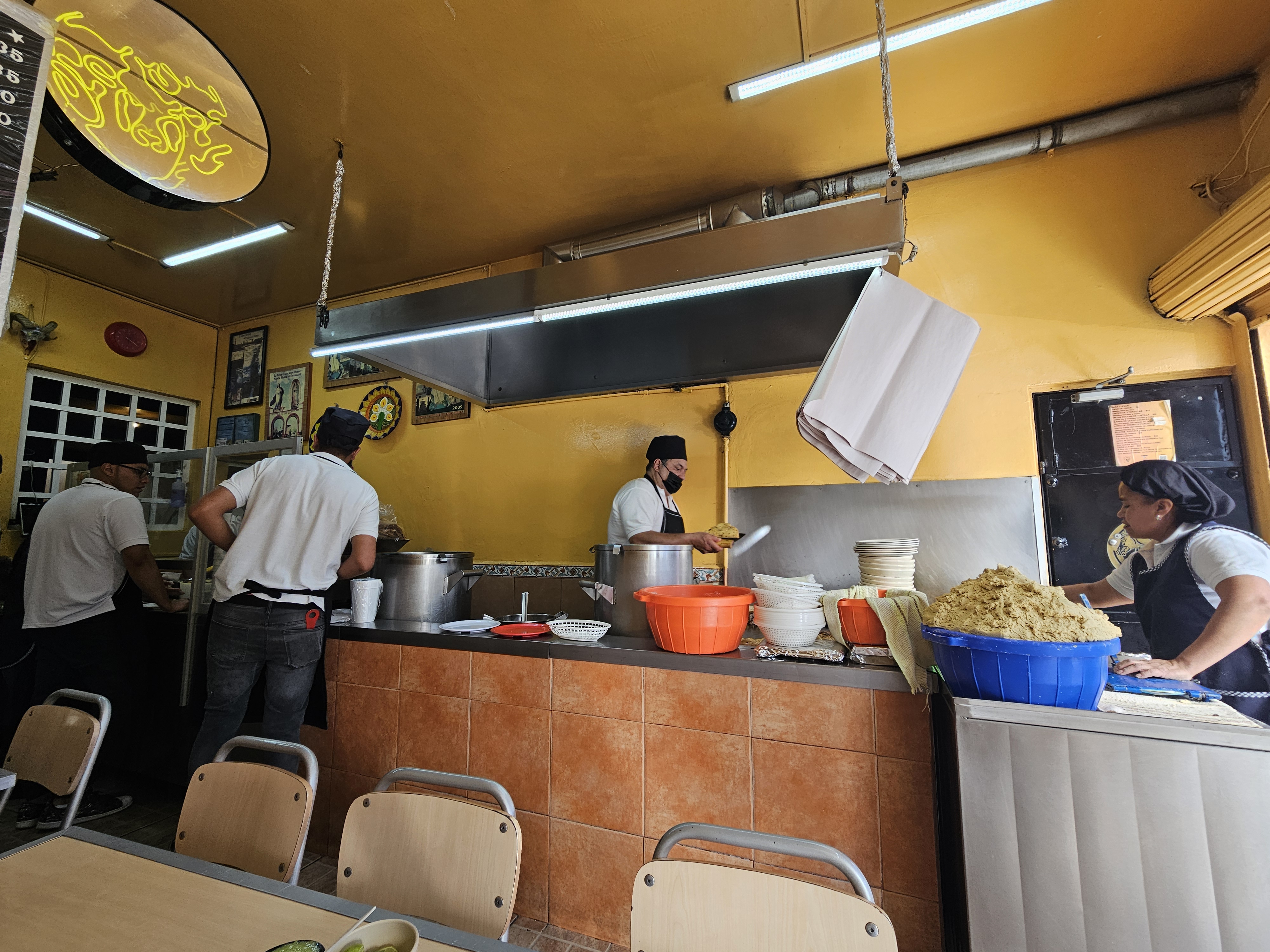La cocina en servicio: el equipo sirviendo de las ollas y la masa lista para echar tortillas a mano
