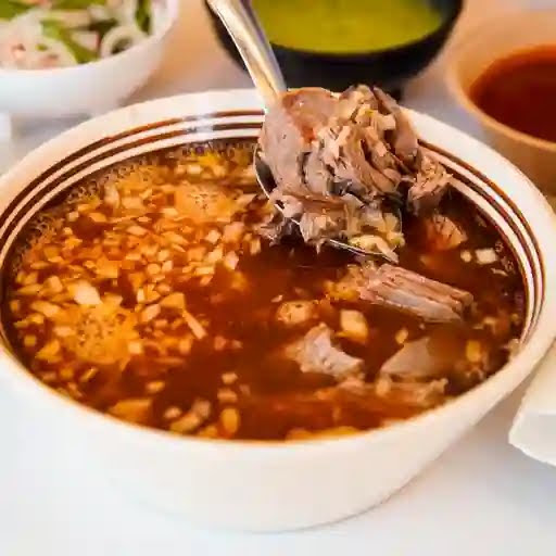 Plato de birria tatemada: la carne de chivo servida con su consomé, cebolla y salsa